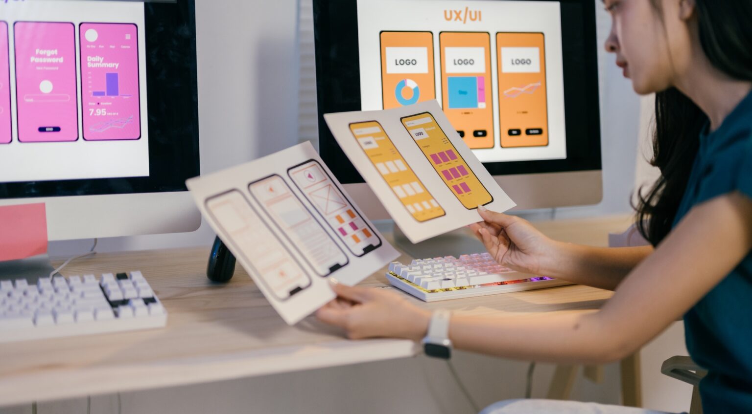 Young ux ui designer comparing paper prototypes to the responsive design on her computer screen, imp