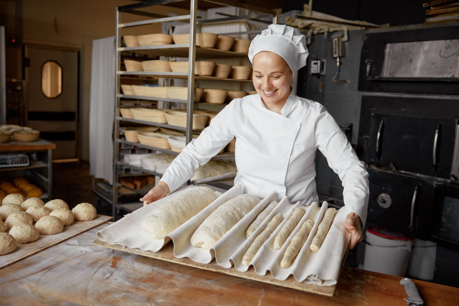Woman baker or pastry cook making fresh bread in local bakery